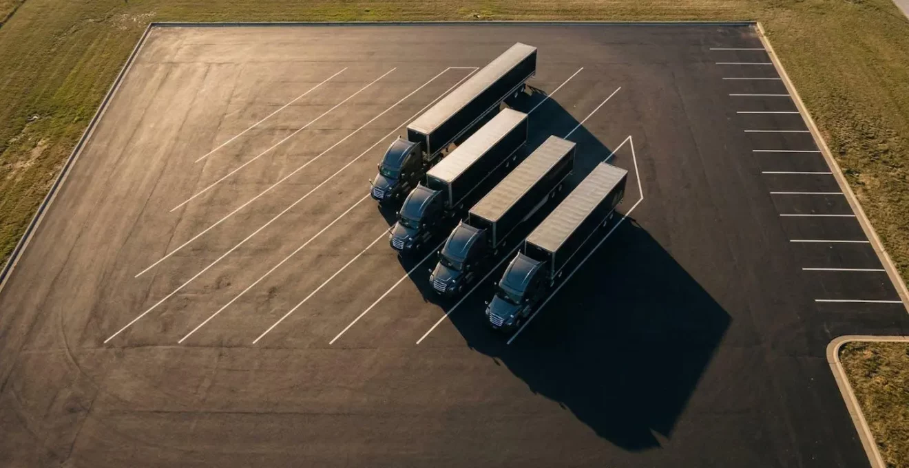 Vue aérienne de plusieurs camions alignés sur une aire de repos, symbolisant la chaîne de sous-traitance dans le transport