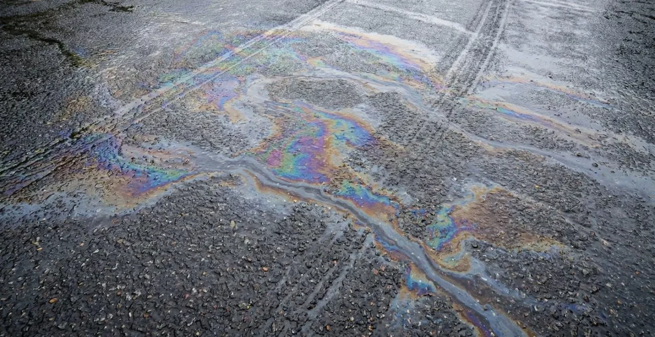 Surface de route mouillée avec reflets irisés d'huile après la première pluie