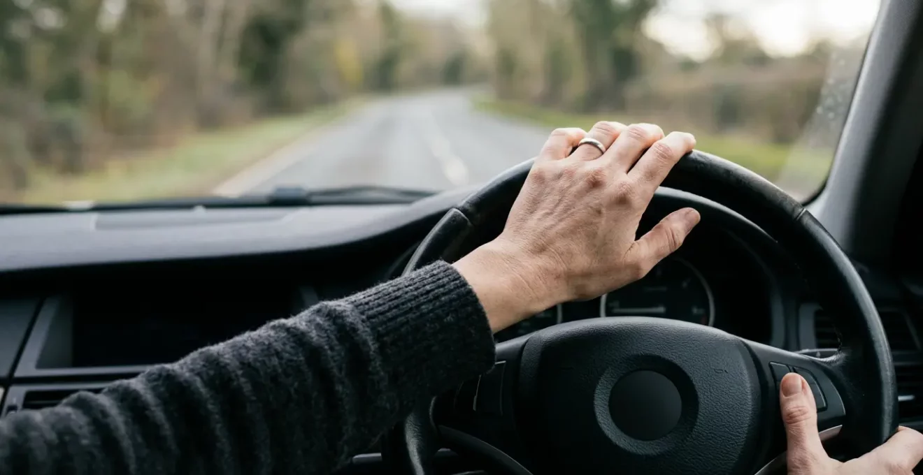 Vue rapprochée d'un volant de voiture avec les mains du conducteur corrigeant légèrement la trajectoire sur une route droite