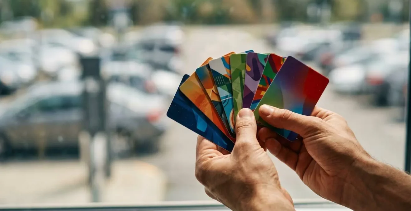 Mains tenant différentes cartes de transport public avec parkings relais en arrière-plan flou