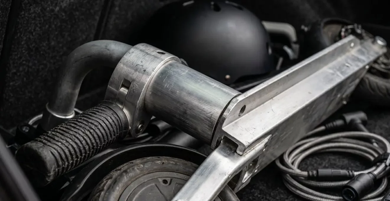 Coffre de voiture ouvert montrant une trottinette électrique pliée rangée avec d'autres équipements